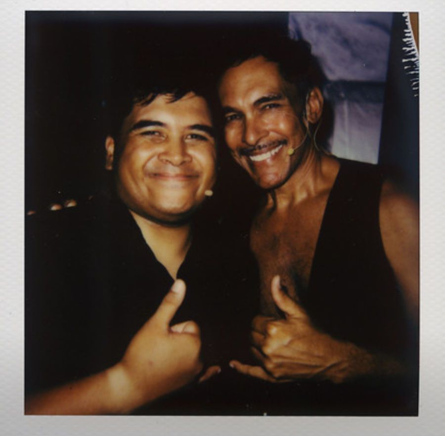 Two men are posing for a picture and one is wearing a headset