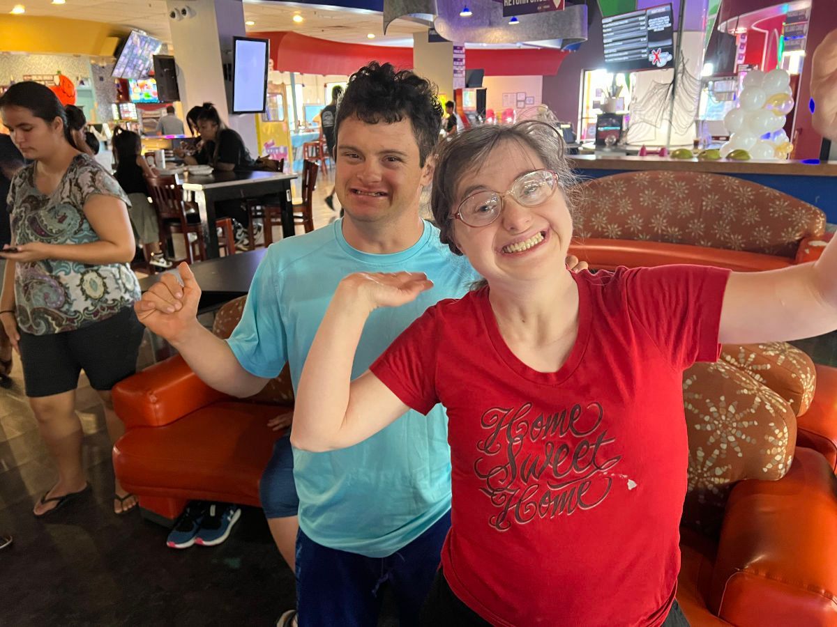 A man and a woman are posing for a picture in a restaurant.
