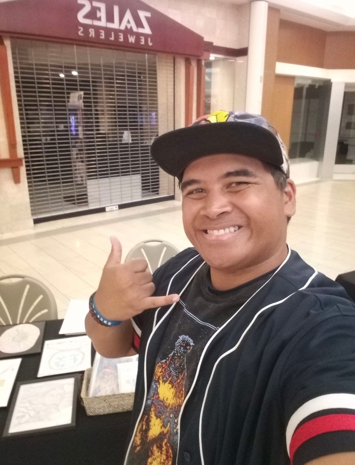 A man wearing a baseball cap is giving a thumbs up