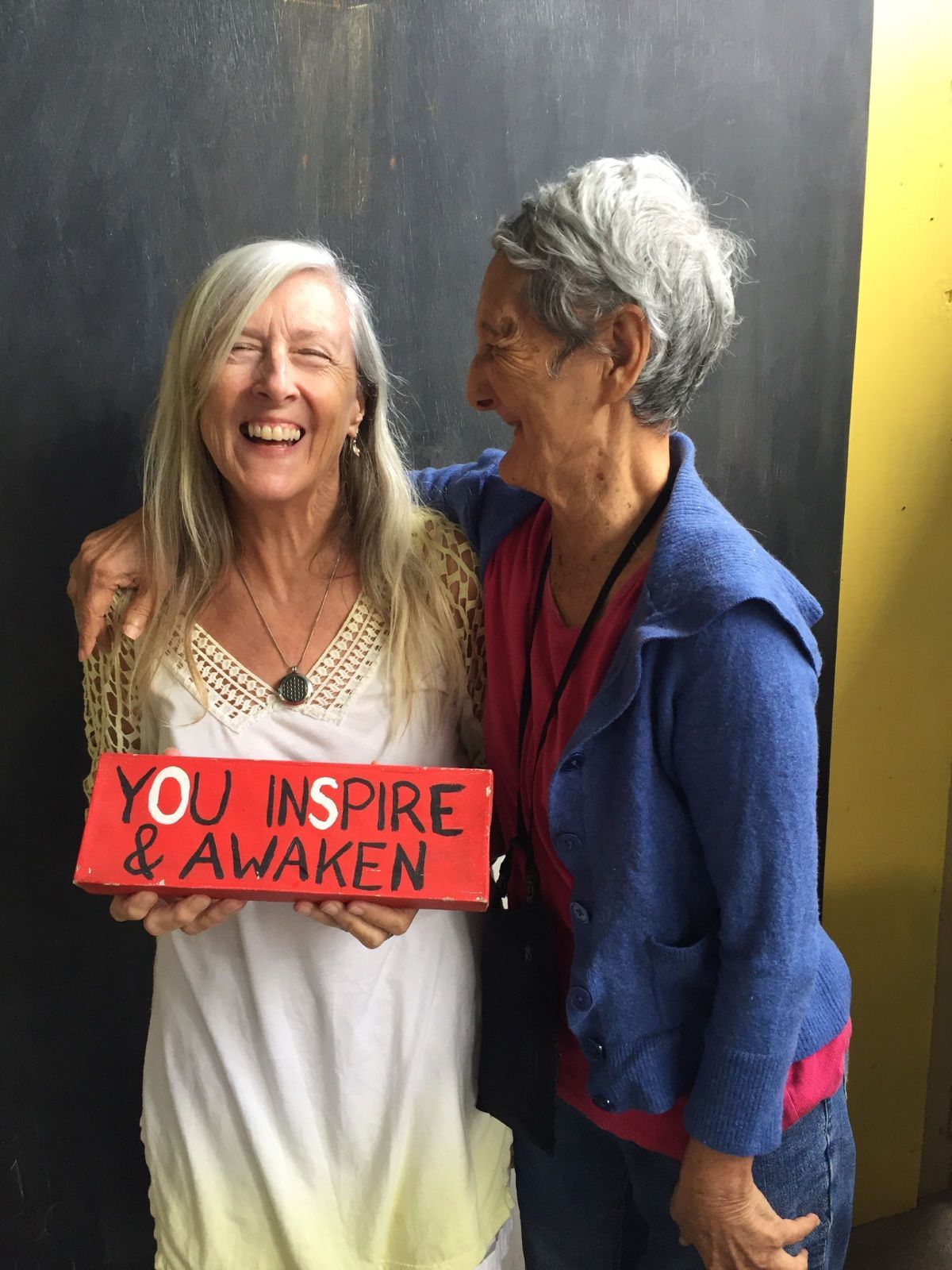 Two women holding a sign that says you inspire and awaken