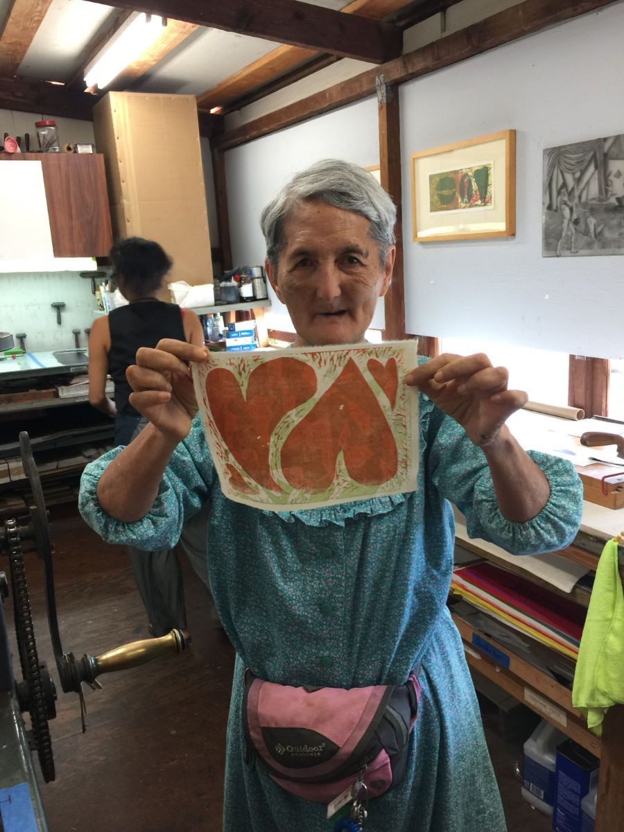 A woman is holding a piece of paper with the letter k on it