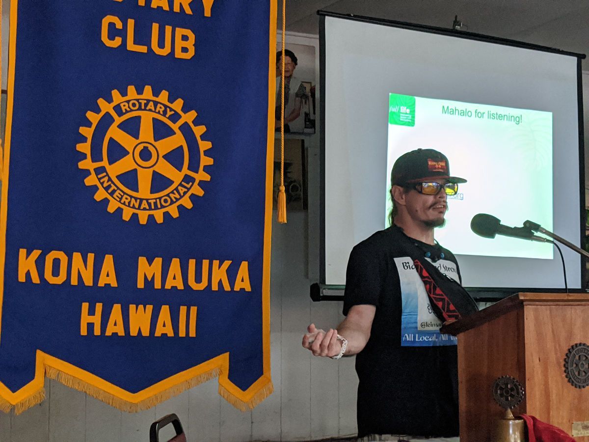 A man is giving a presentation in front of a rotary club banner