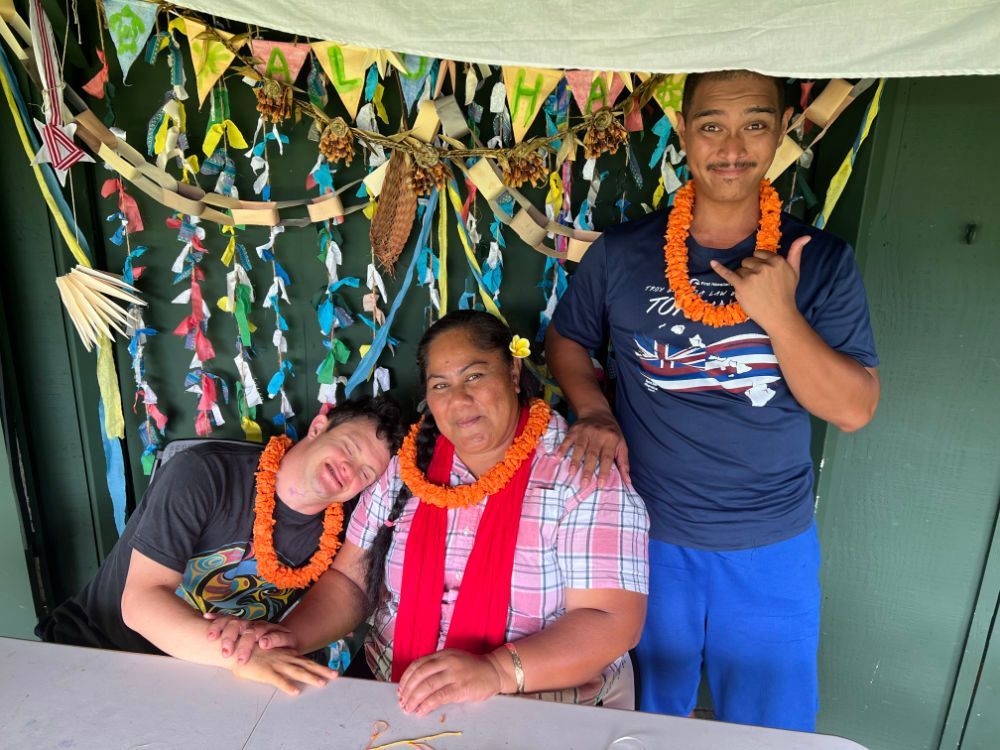 A group of people posing for a picture with one wearing a lei