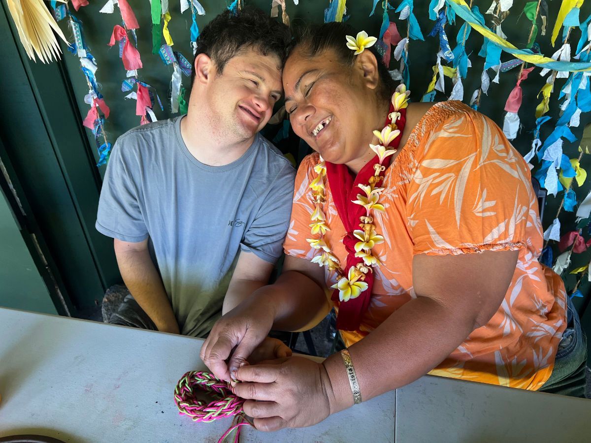 A man and a woman are sitting at a table . the woman is wearing a lei.