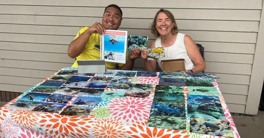 A man and a woman are sitting at a table holding pictures.