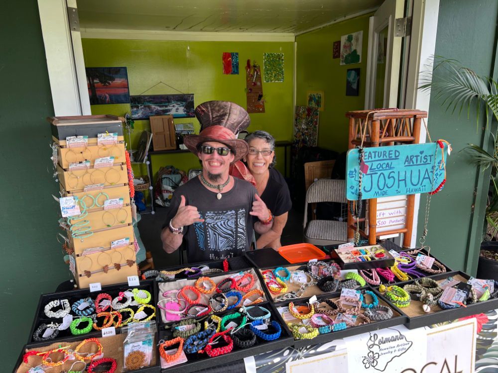 A man and woman are standing in front of a table with bracelets on it.