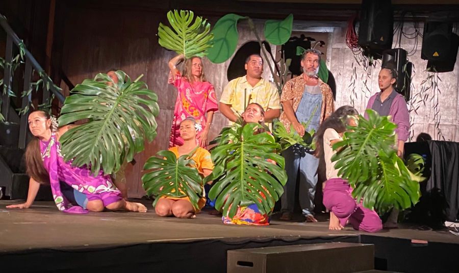 A group of people are standing on a stage holding leaves.