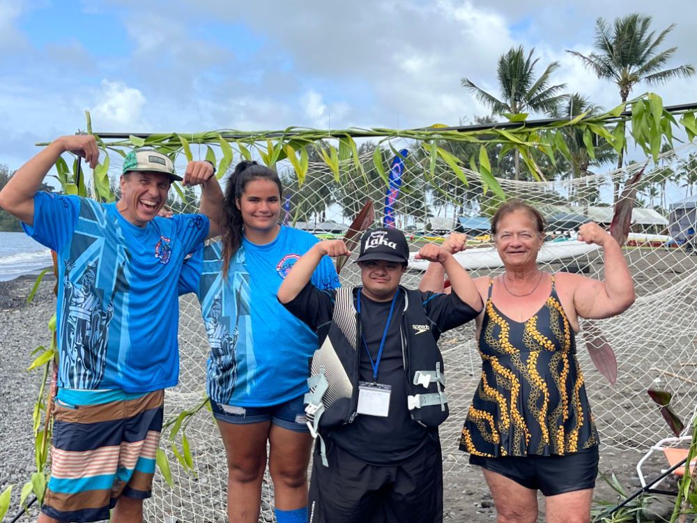 A group of people are posing for a picture on a beach.