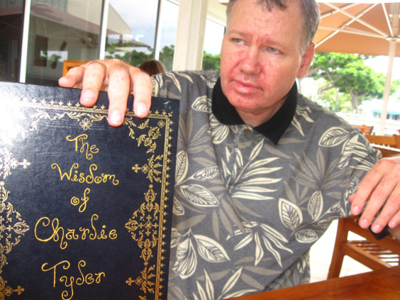 A man is holding a book titled the wisdom of charlie taylor