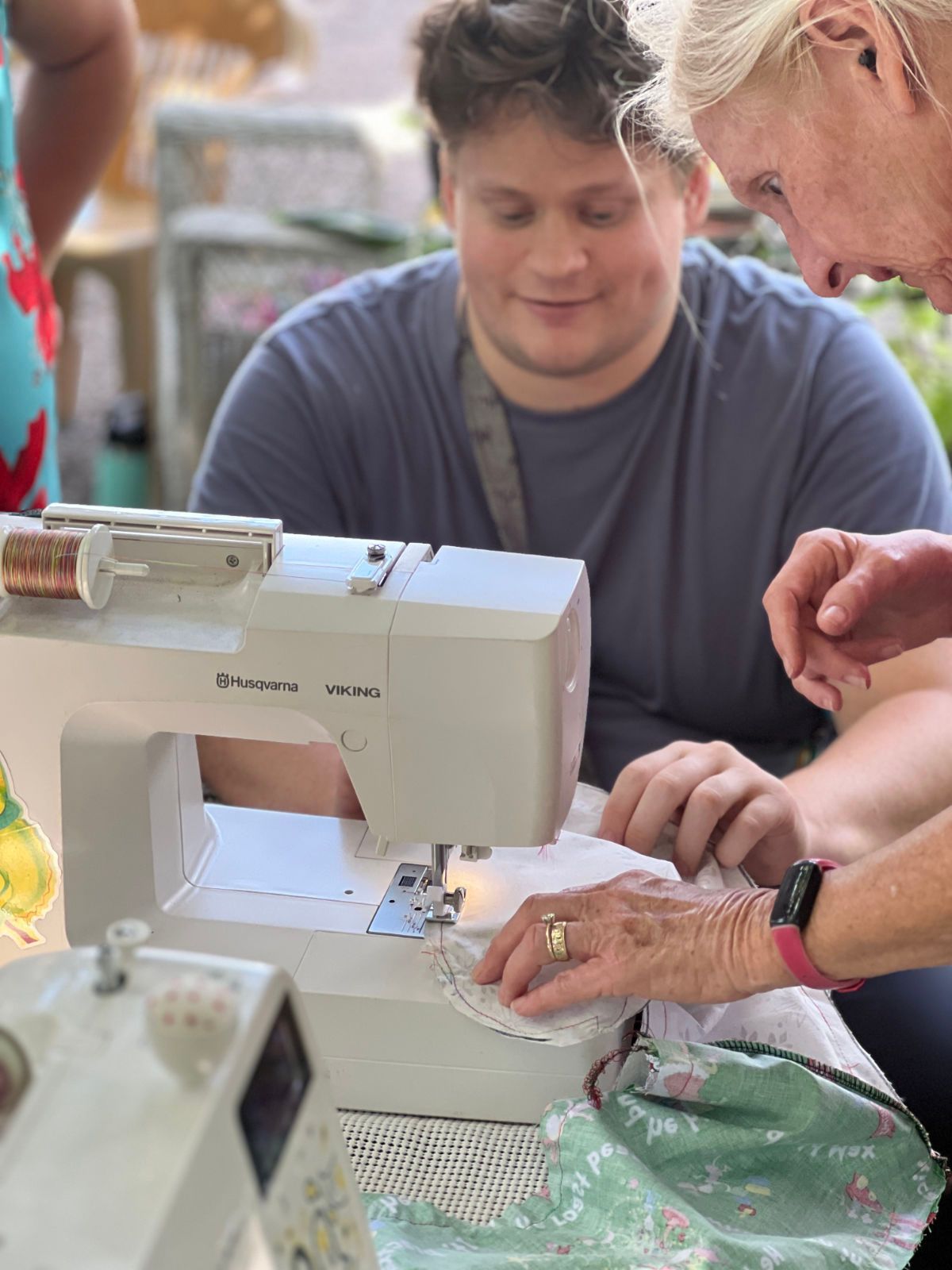 A woman is teaching a man how to use a sewing machine.