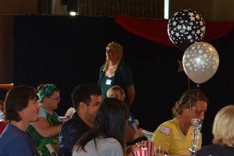 A group of people are sitting at a table with balloons in the background.