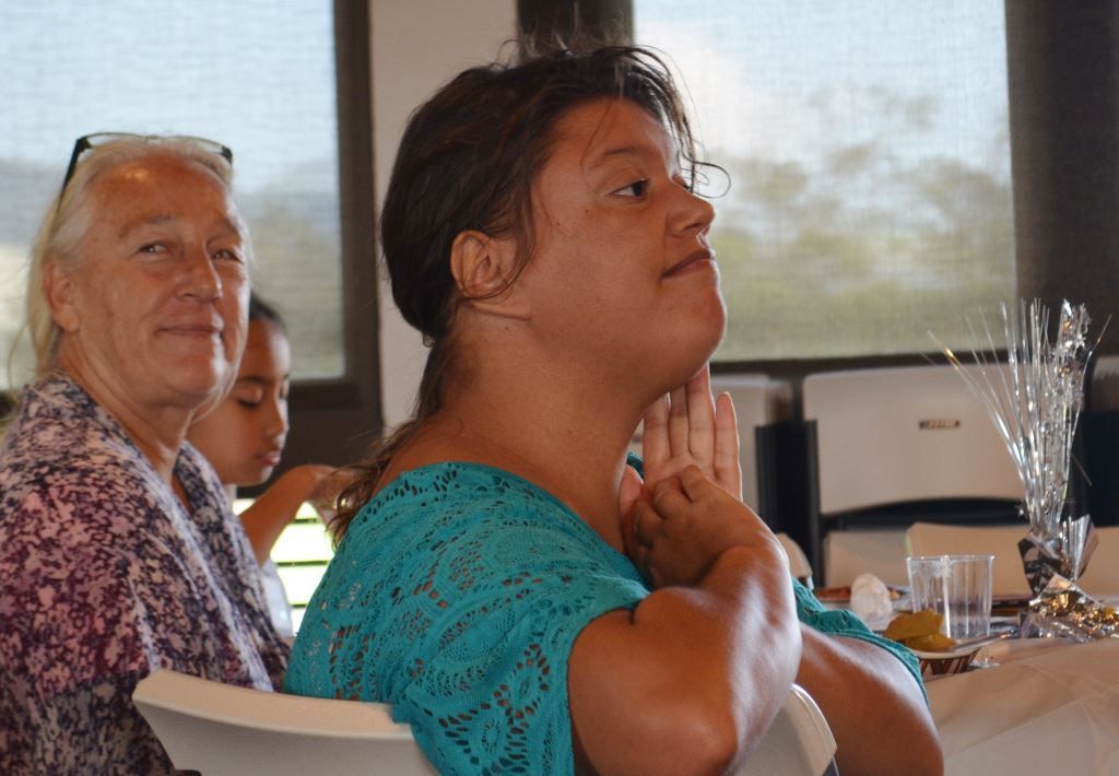 A woman in a blue shirt is sitting at a table with other women.