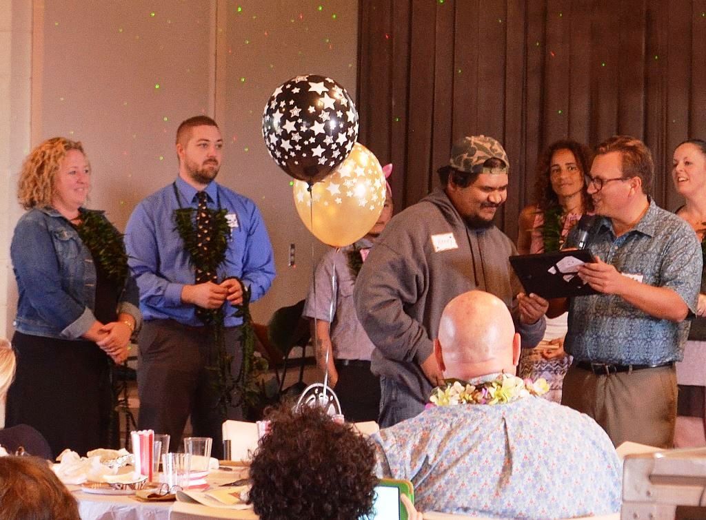 A group of people standing around a table with balloons in the background