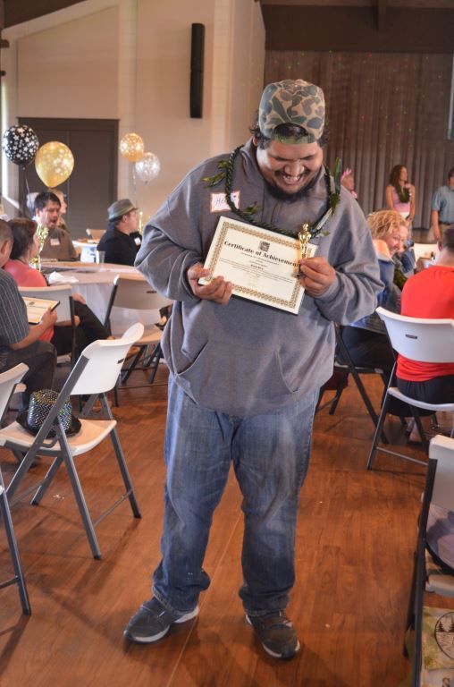 A man is standing in a room holding a certificate.
