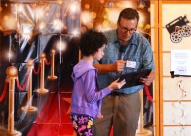 A man and a little girl are standing on a red carpet.