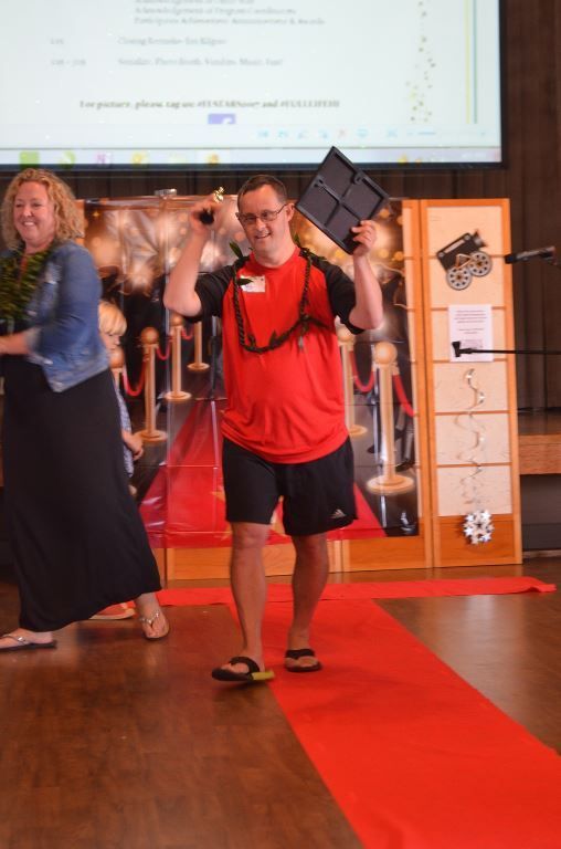 A man in a red shirt is walking down a red carpet