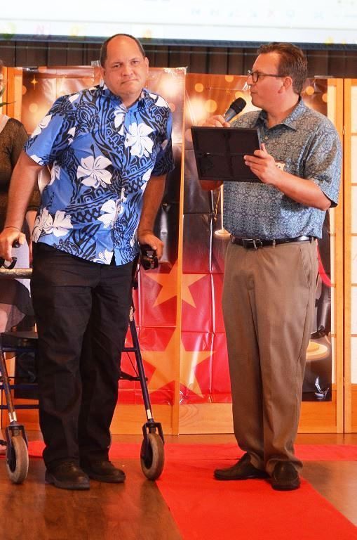 A man in a blue shirt is talking to another man in a walker