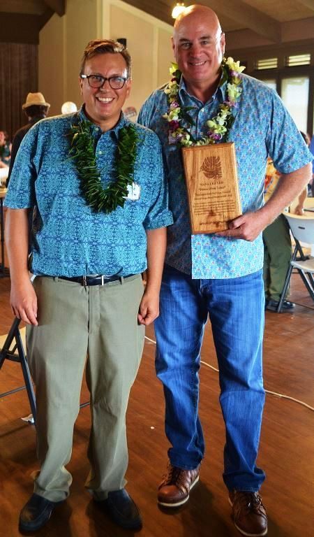 Two men are standing next to each other holding a plaque.
