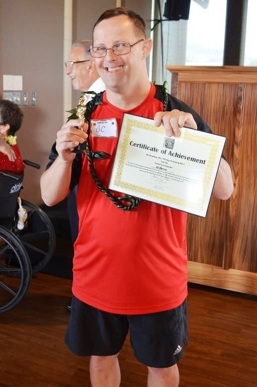 A man in a red shirt is holding a certificate of achievement