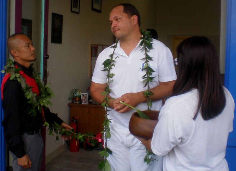 A man wearing a lei is talking to two women
