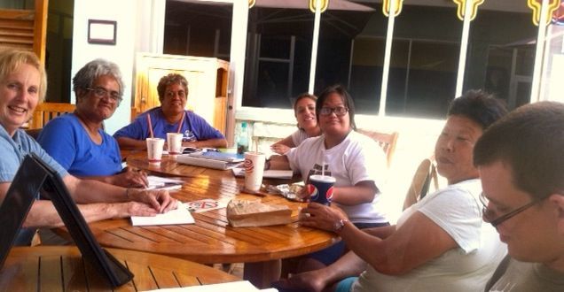 A group of people are sitting around a table with a pepsi cup
