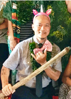 A man wearing a unicorn headband is holding a stick