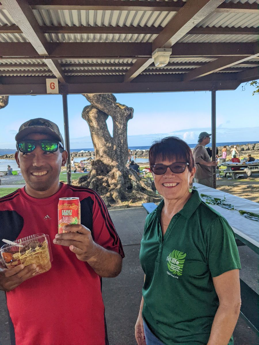 A man and a woman are standing under a canopy holding snacks