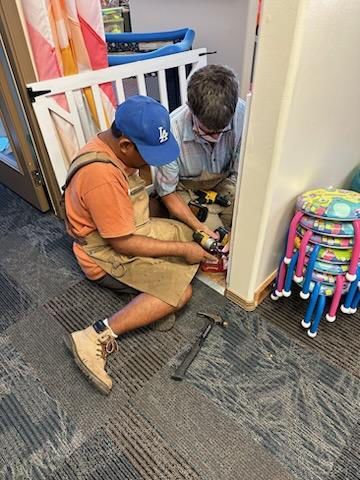 A man and a boy are working on a door in a room.