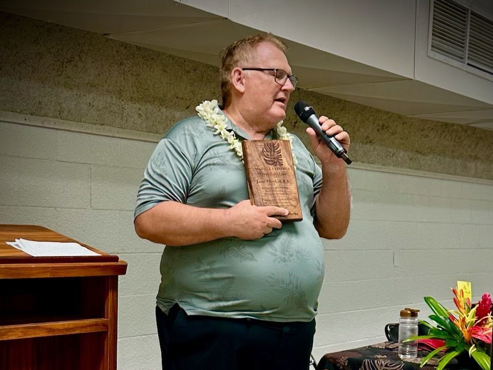 A man is holding a book and speaking into a microphone