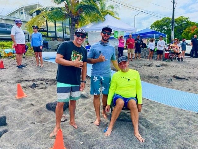 Three men are posing for a picture on the beach