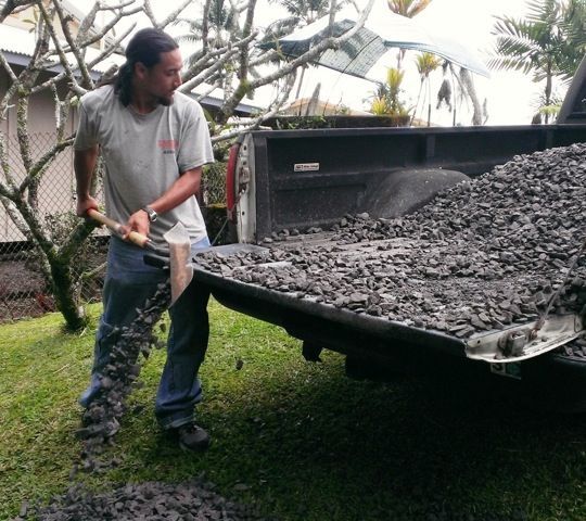 A man is digging in the back of a truck with a shovel