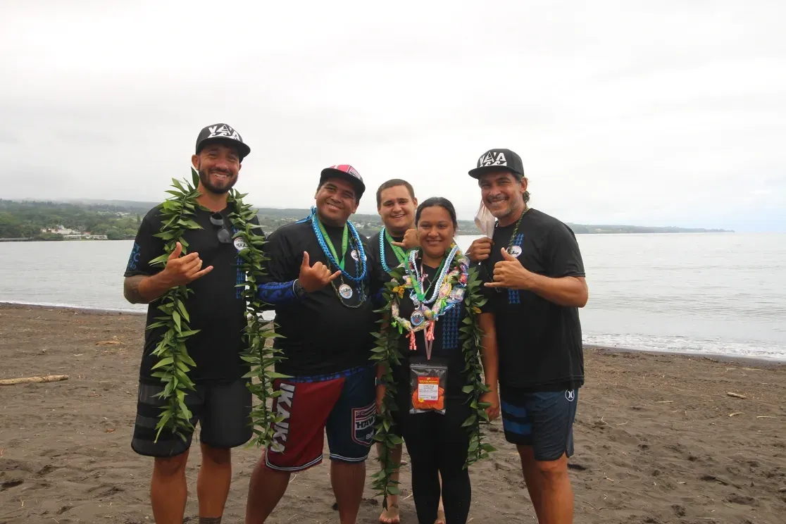 A group of people are posing for a picture on a beach.