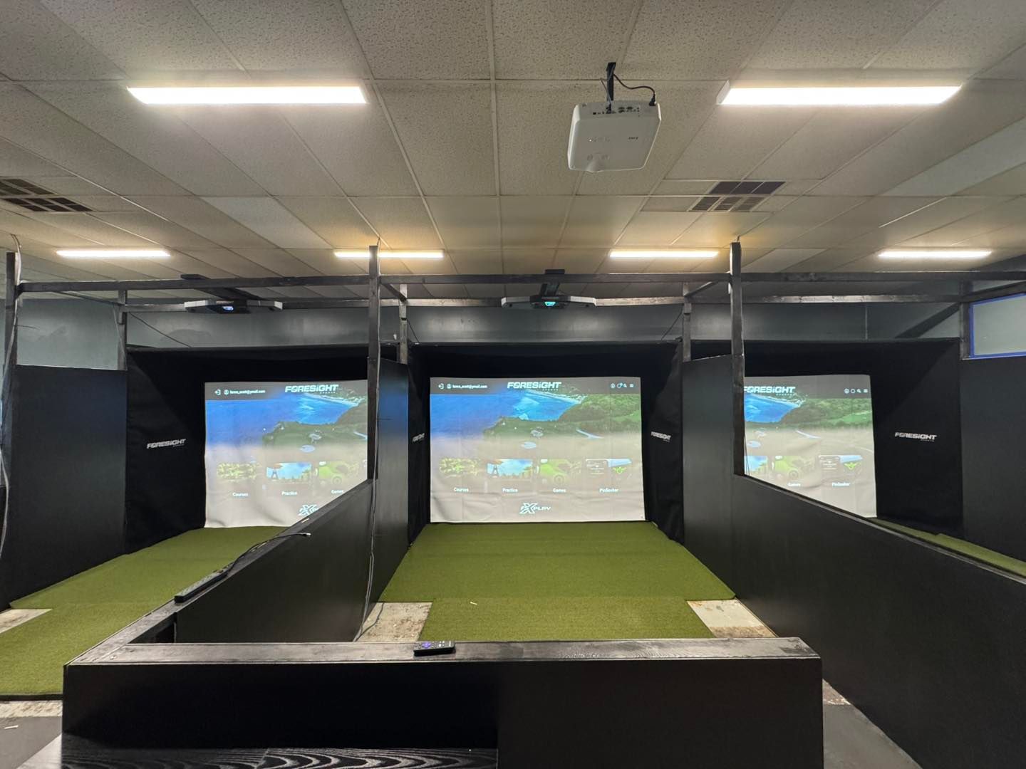 A golf simulator with a projector hanging from the ceiling.