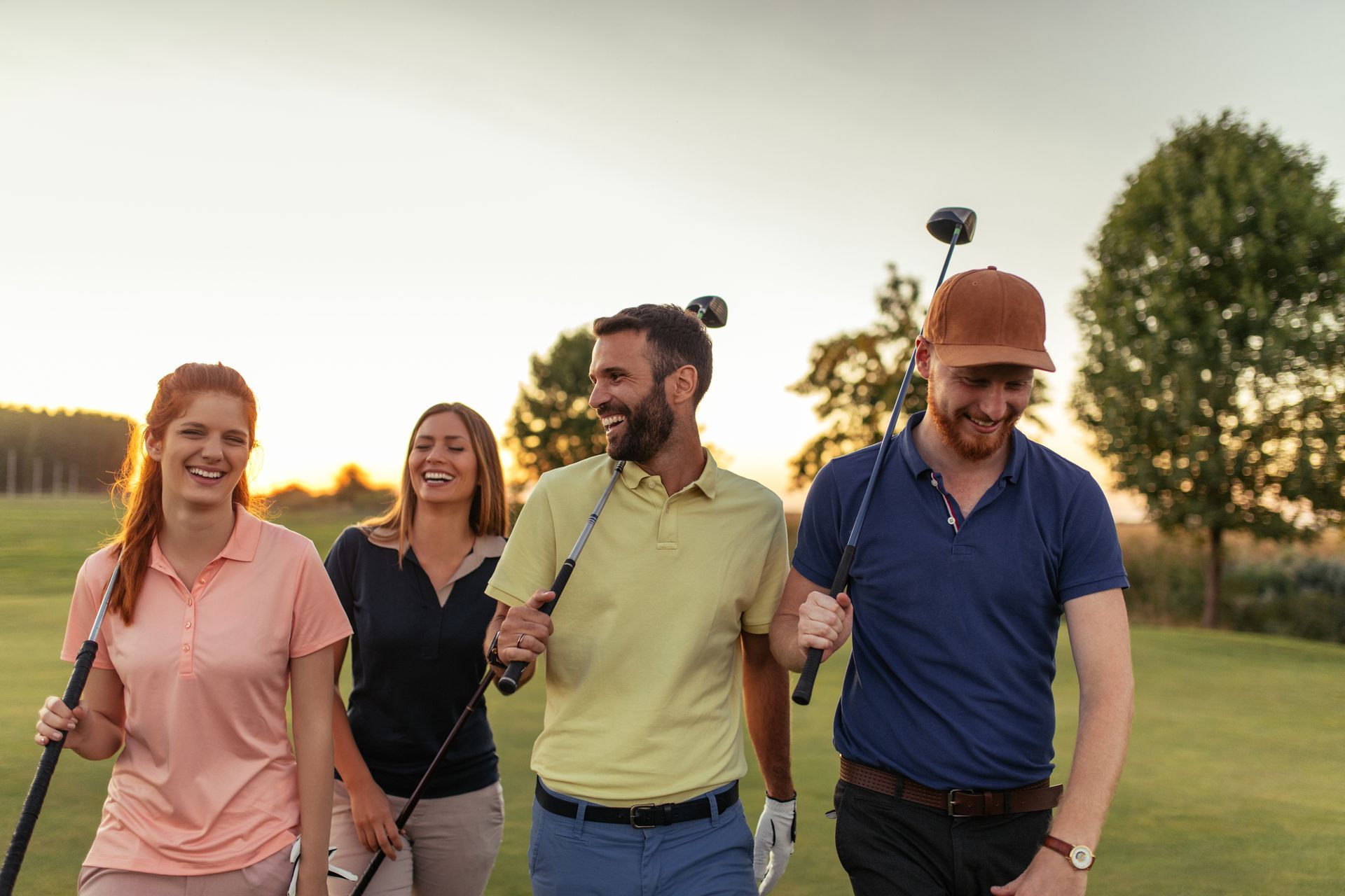 A group of people are walking down a golf course holding golf clubs.
