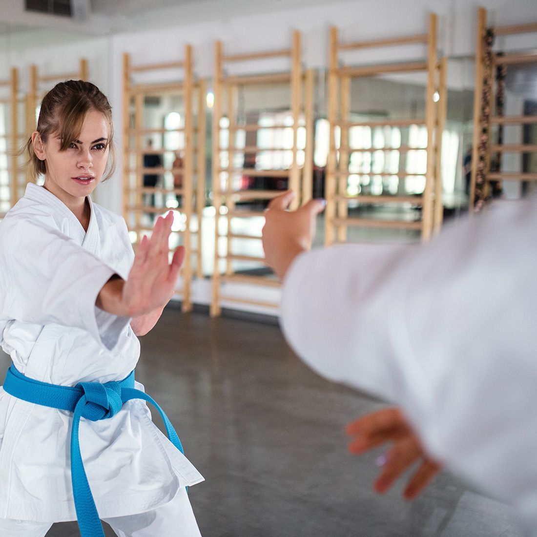 a woman with a blue belt is practicing karate