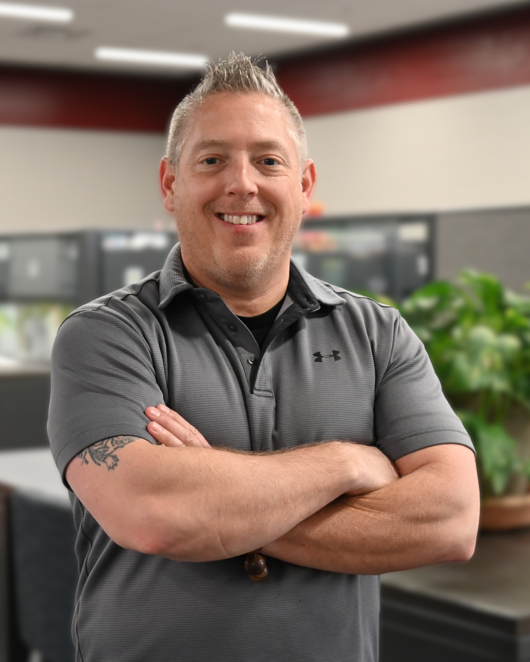 Man smiling, wearing a red shirt and striped tie, against a gray background.