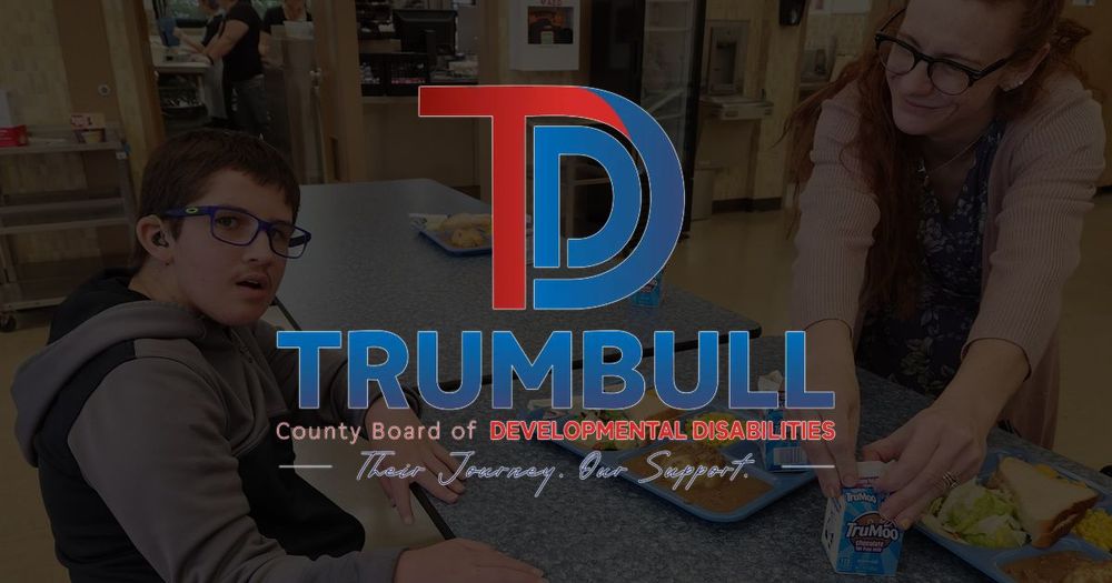 Logo for Trumbull County Board of Developmental Disabilities with people, indoors. Woman and man sitting at a table with food.