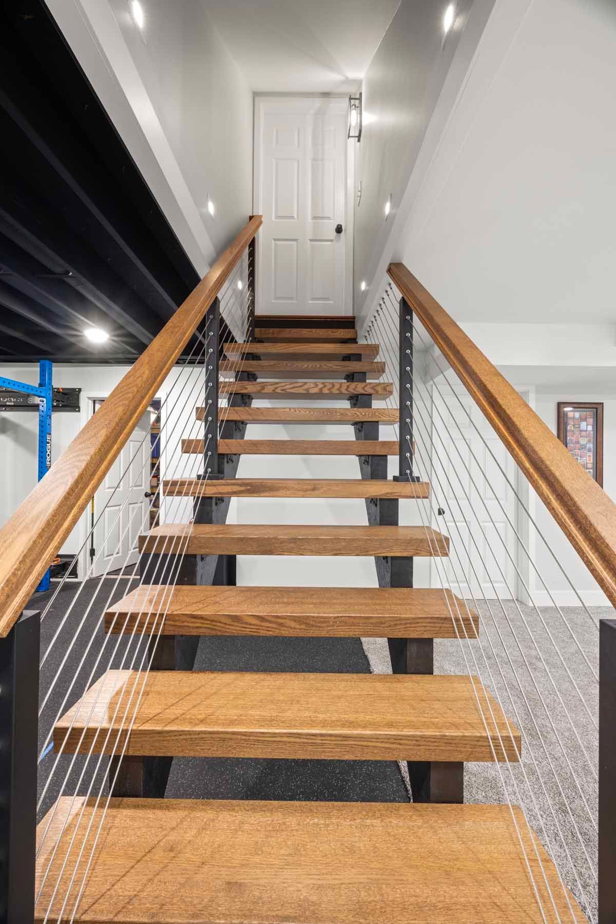 Wooden staircase with metal railing leads to a white door at the top.