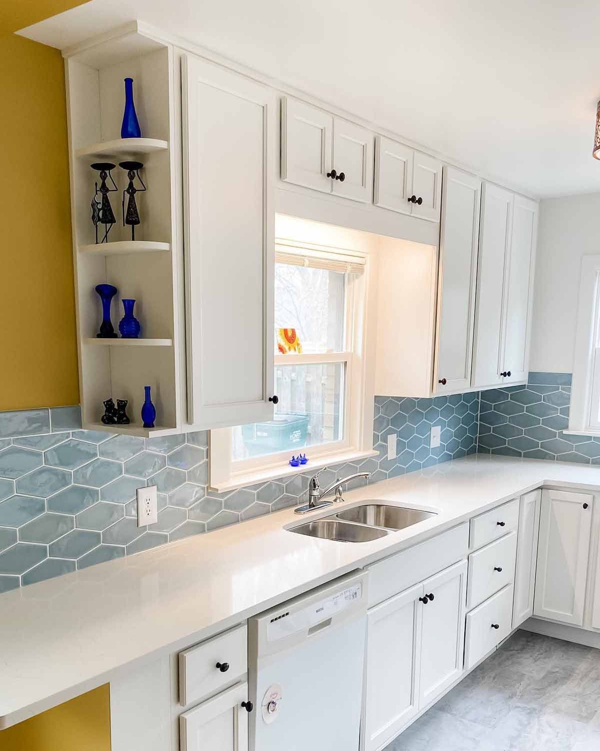 White kitchen with blue tile backsplash, white cabinets, and a yellow wall.