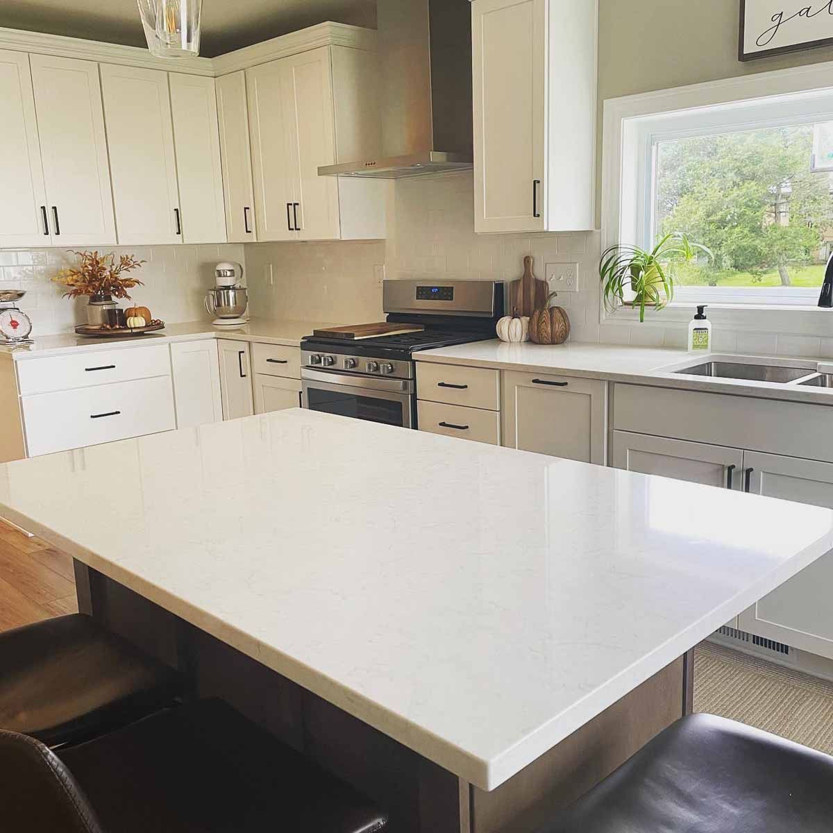 Bright white kitchen with a large island, white cabinets, and stainless steel appliances.