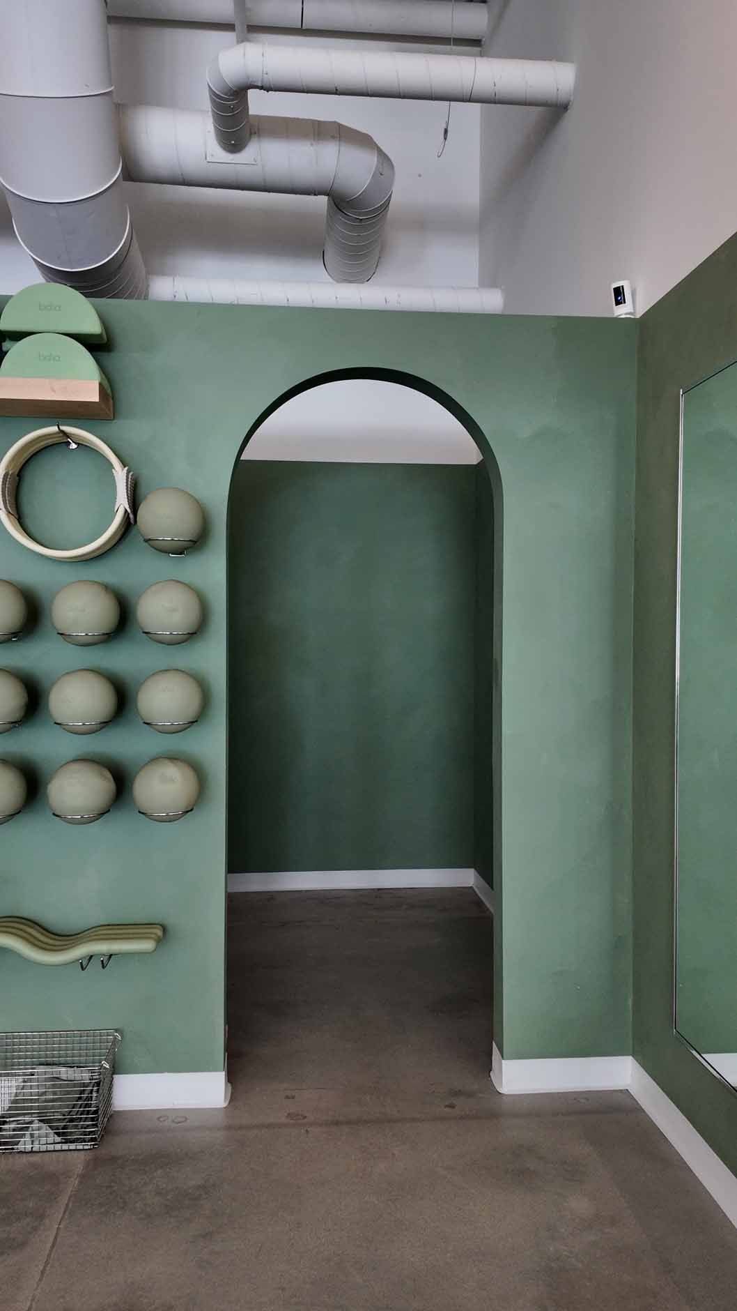 Green arched doorway in a room with a textured green wall, modern decor.