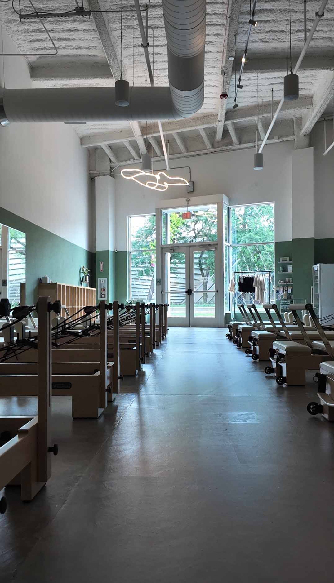 Pilates studio interior with workout equipment, open doors to outdoor view. Bright, natural light.