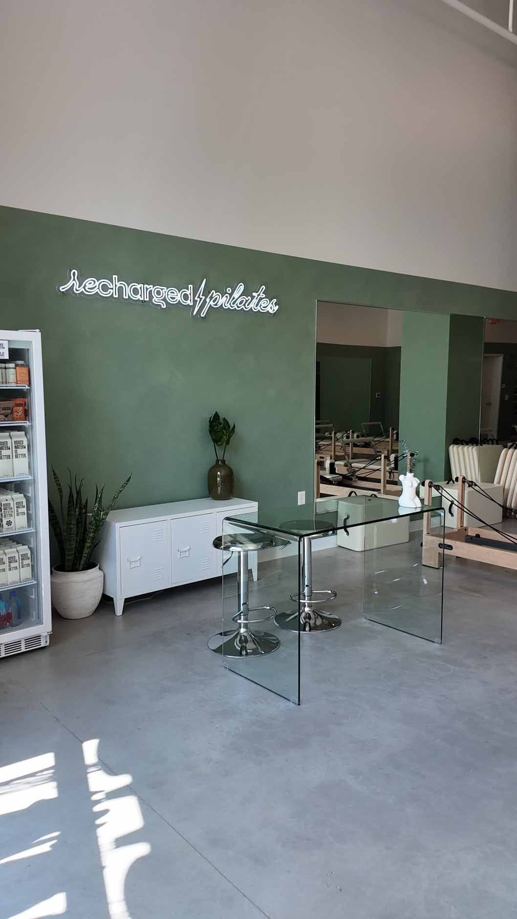 Interior of a business with green walls, a white cabinet, a glass table, and a sign.