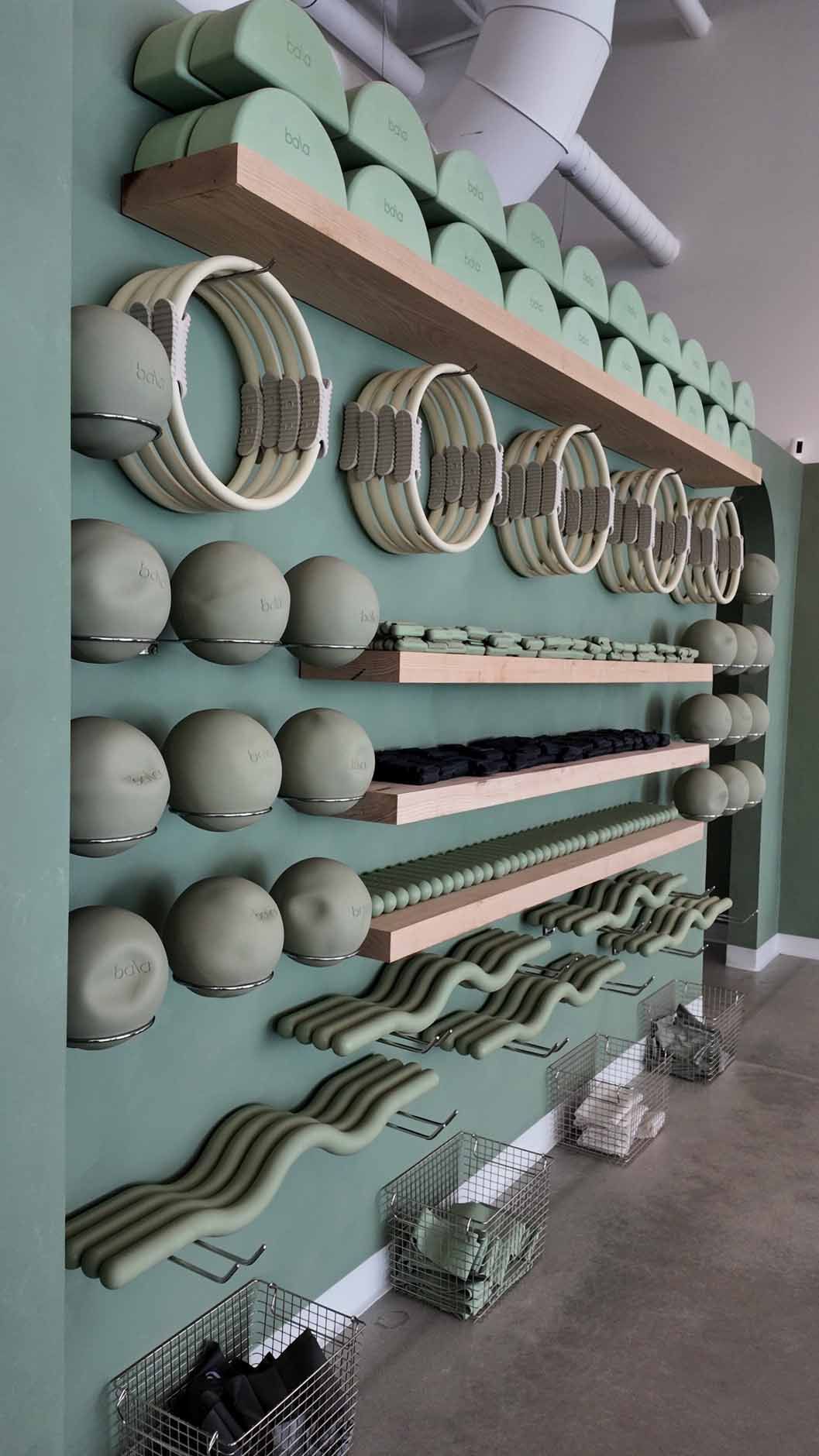 A wall with green shelves displaying exercise equipment in a gym setting.