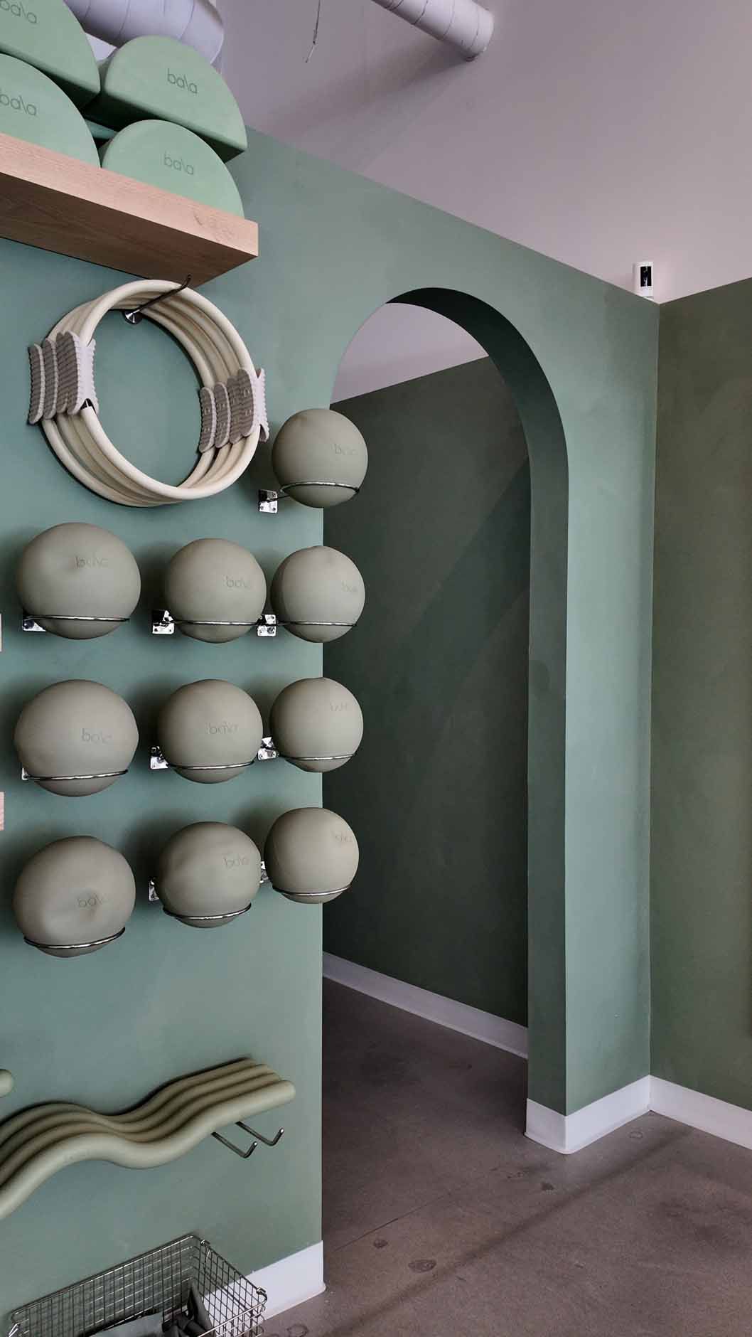 Green-painted interior with arched doorway, wall-mounted spheres, and shelving.