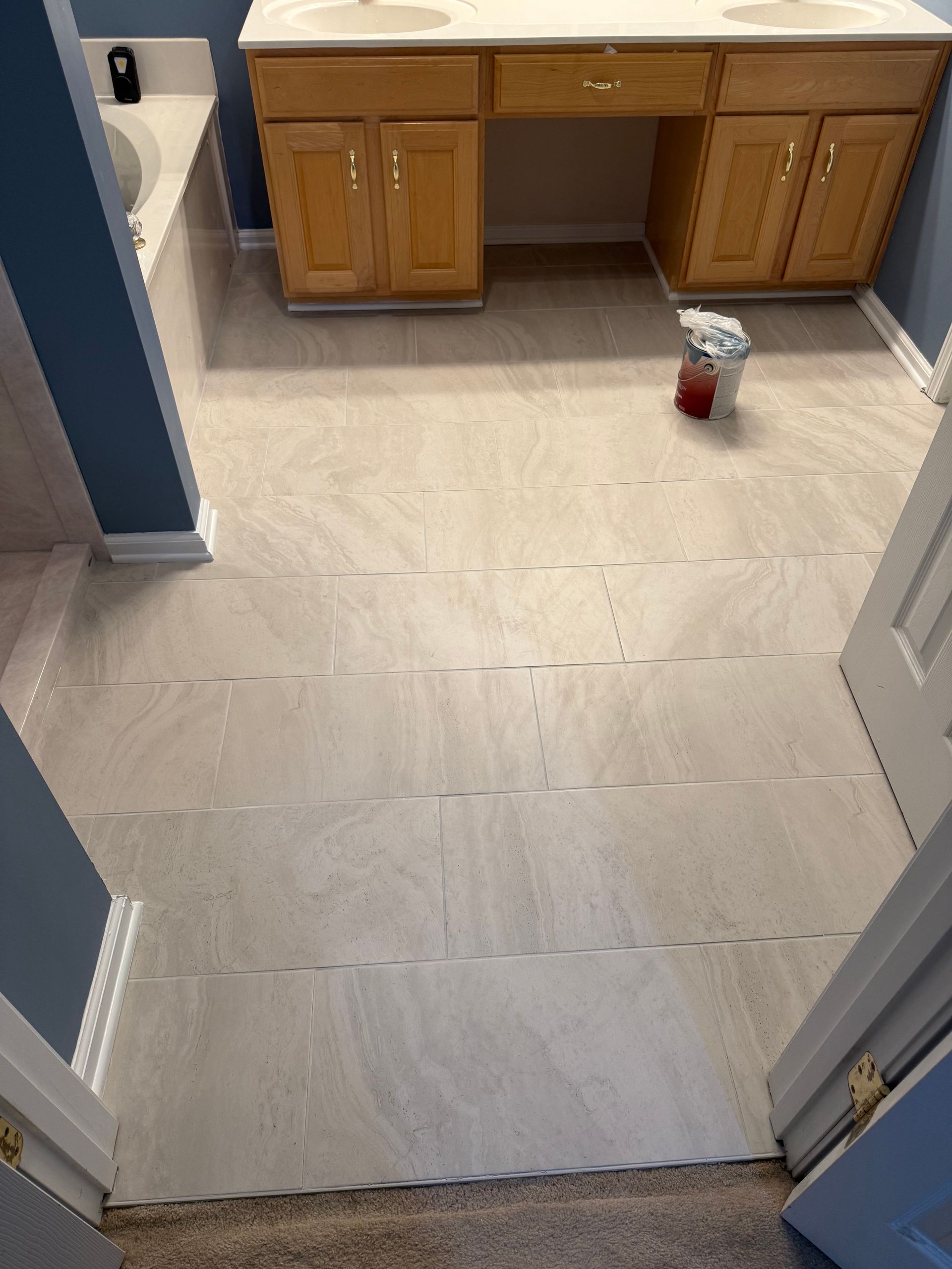 Bathroom with beige tile floor, wooden cabinets, and blue walls.