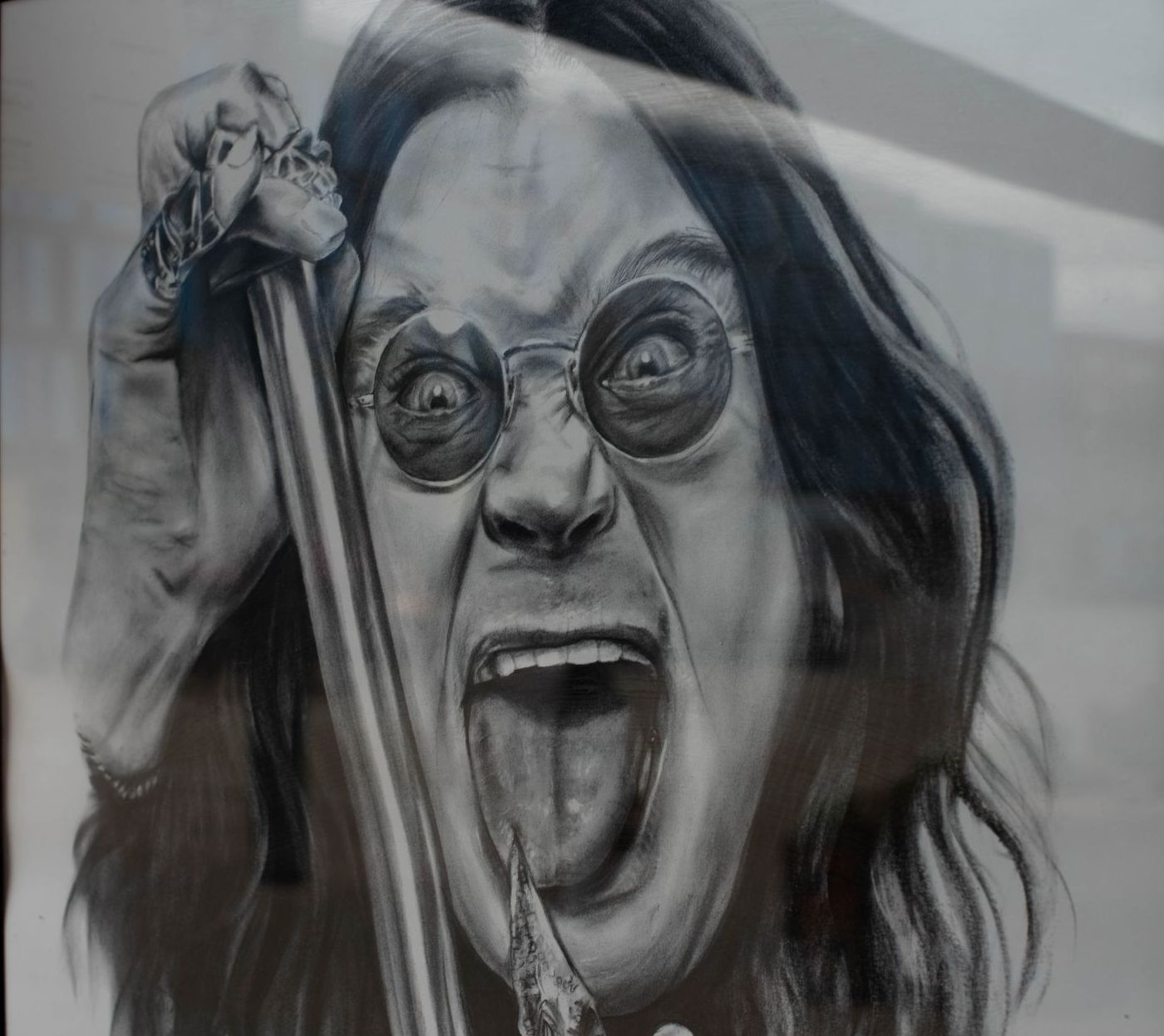 Charcoal drawing of Ozzy Osbourne sticking out his tongue, holding a microphone, with a crazed expression.
