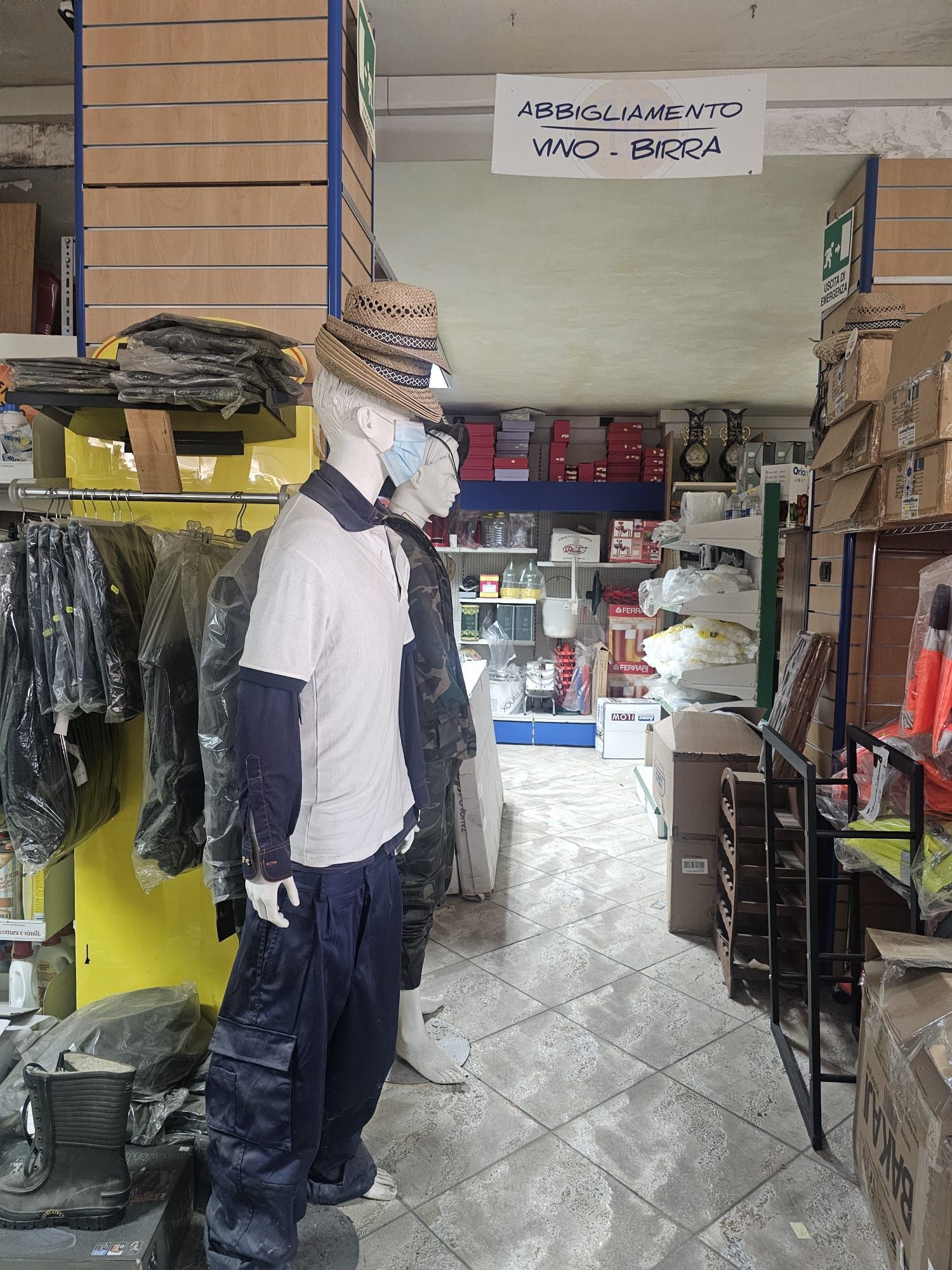 Un uomo che indossa un cappello e una maschera è in piedi accanto a un manichino in un negozio.