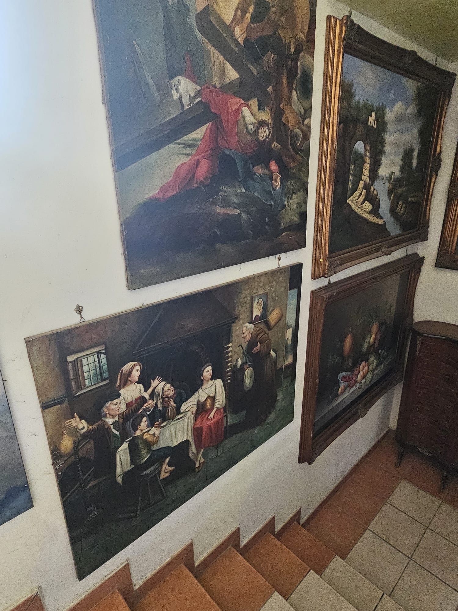 Un gruppo di dipinti è appeso su una parete accanto alle scale.