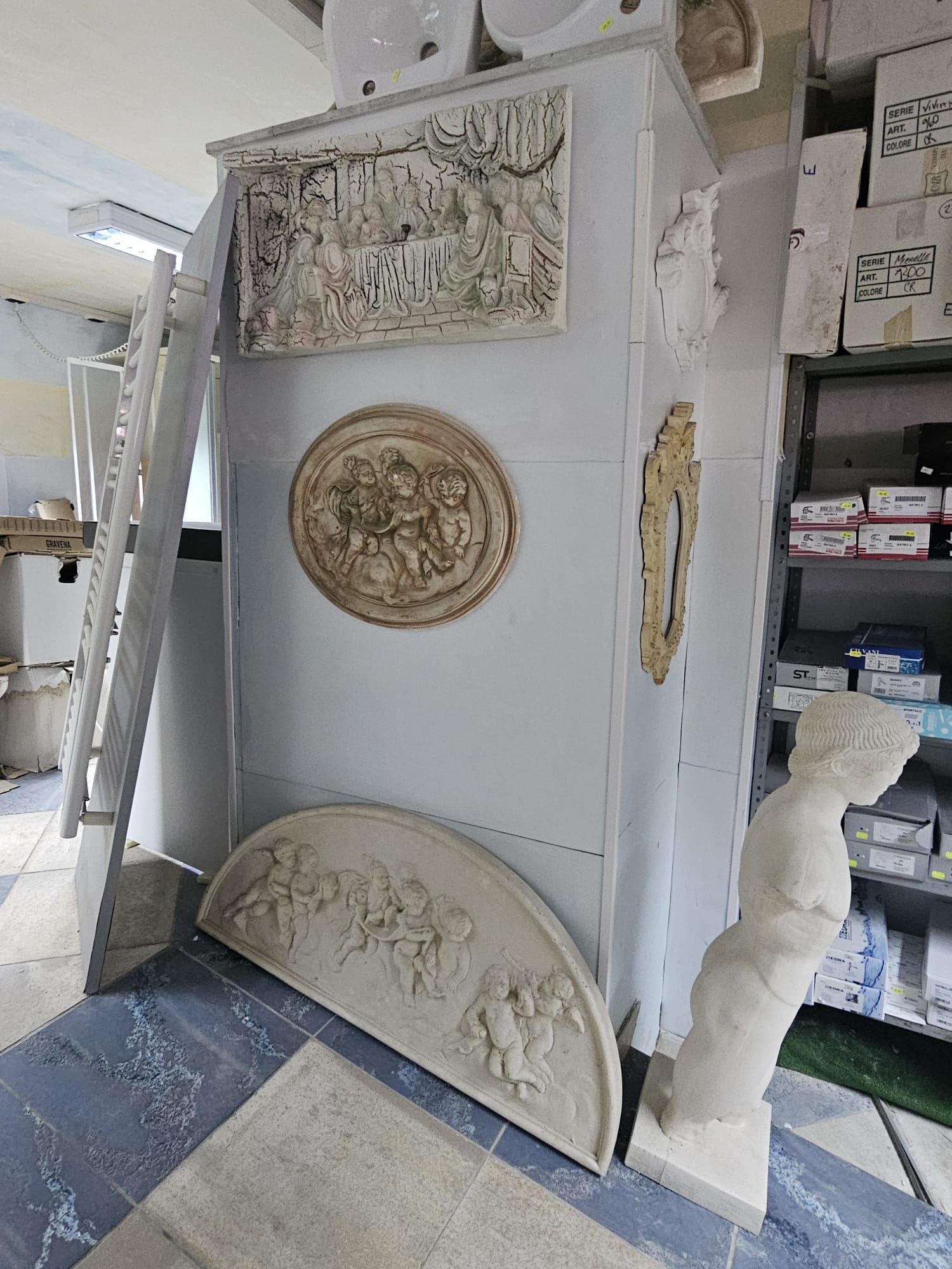 Una stanza con molte sculture sul muro e una statua sul pavimento.